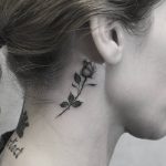 A grey rose tattoo on neck